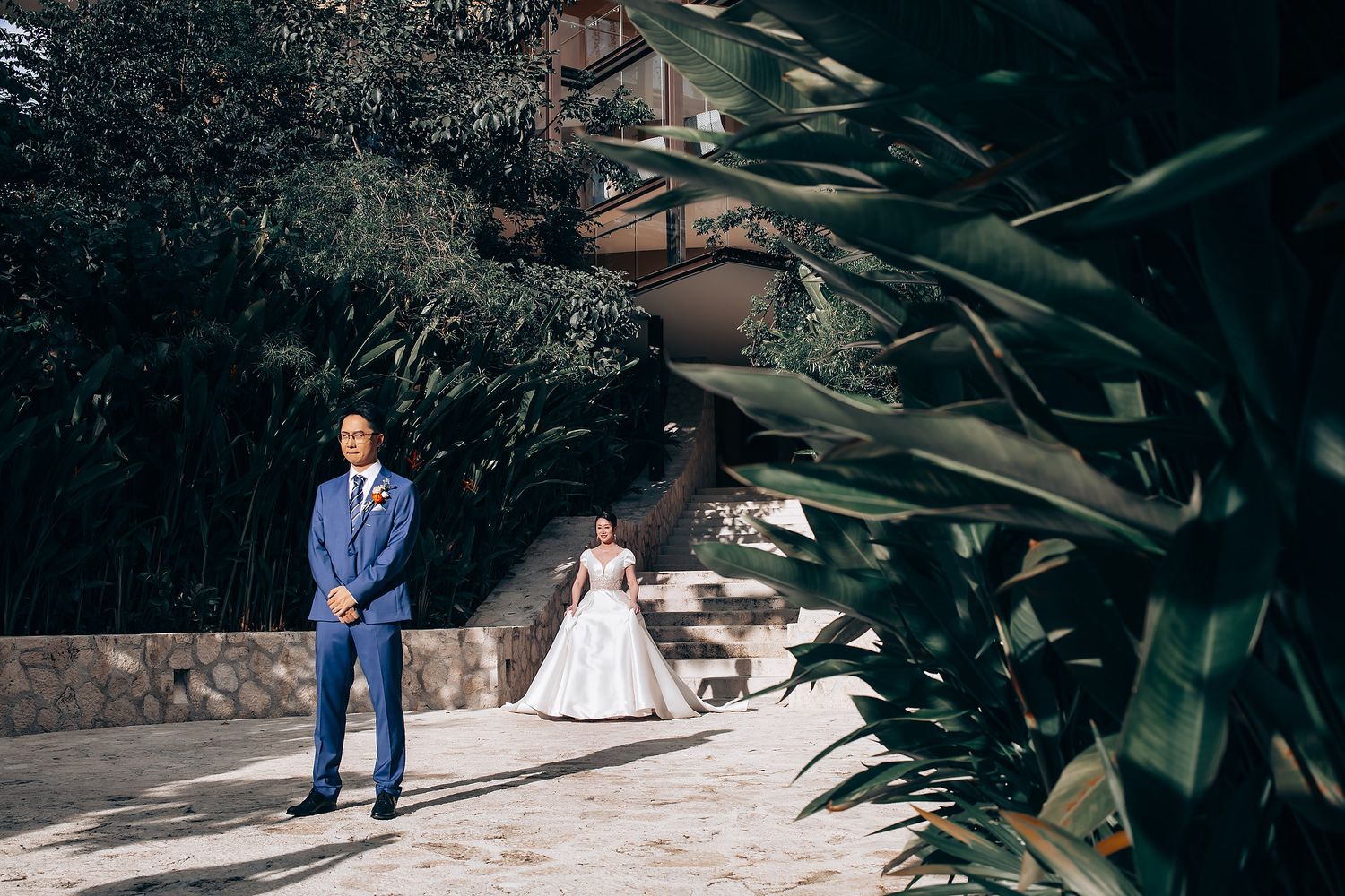 Outdoor garden wedding photography session with tropical plants in the background.