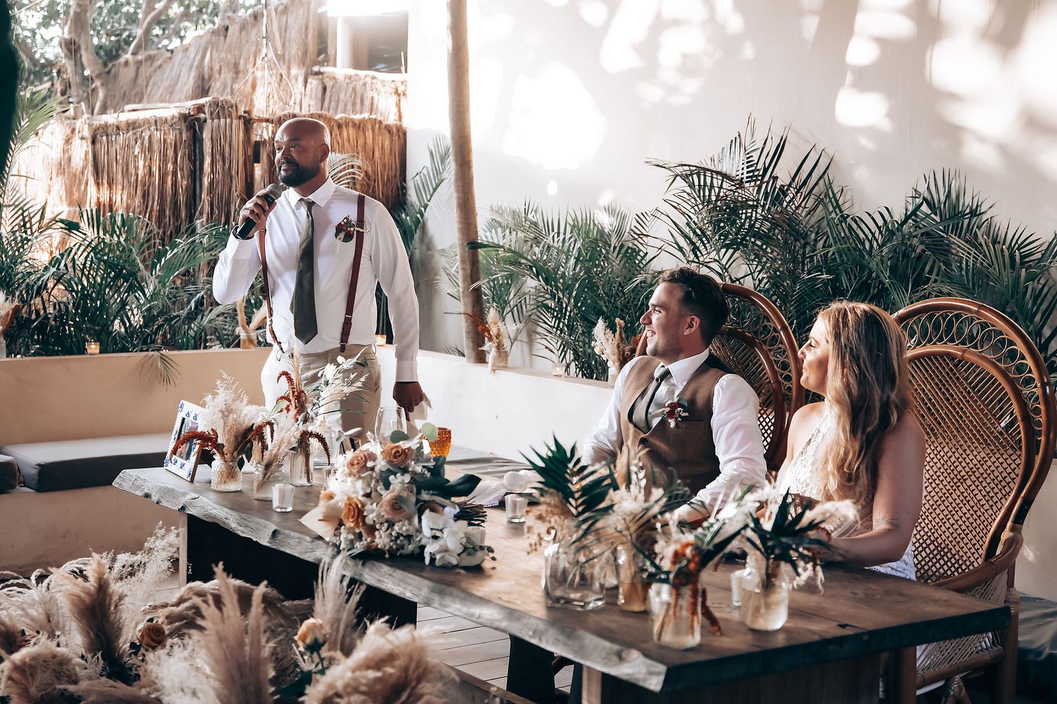 Diners seated at wooden tables in a bohemian-style cafe with peacock chairs and tropical decor.