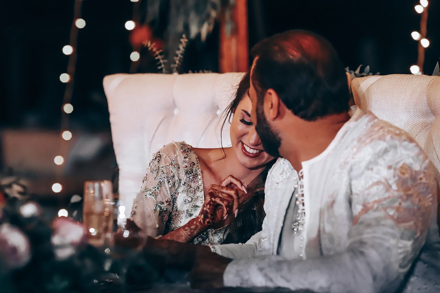 A couple shares a romantic moment during their wedding reception while guests celebrate in the background.