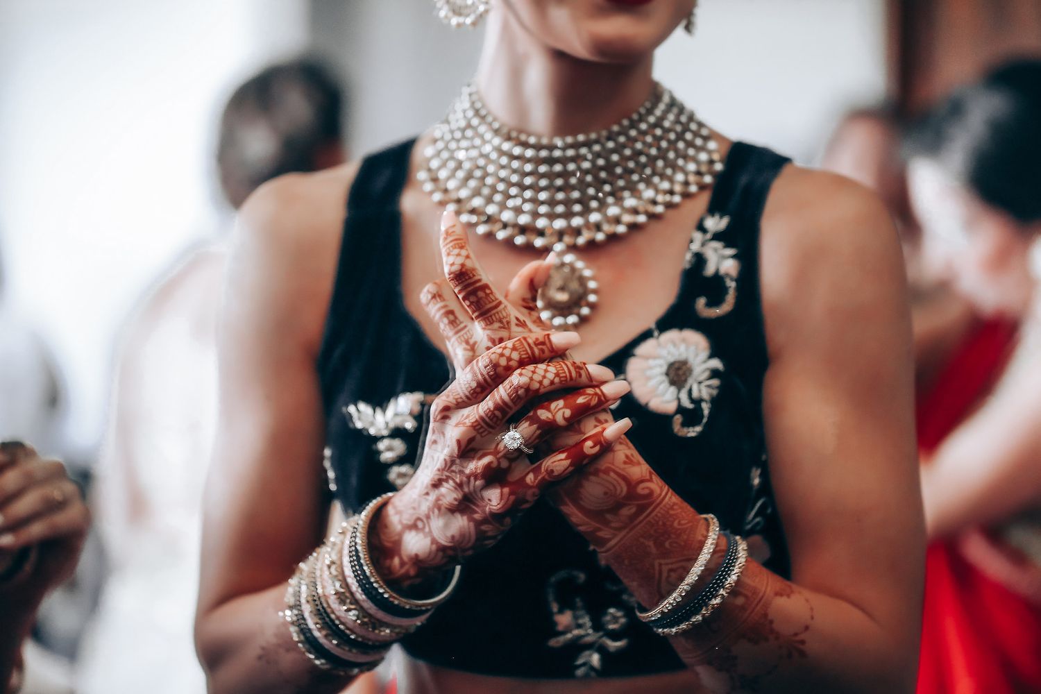 Detailed view of elegant bridal jewelry and mehndi adorned hands during wedding preparations.