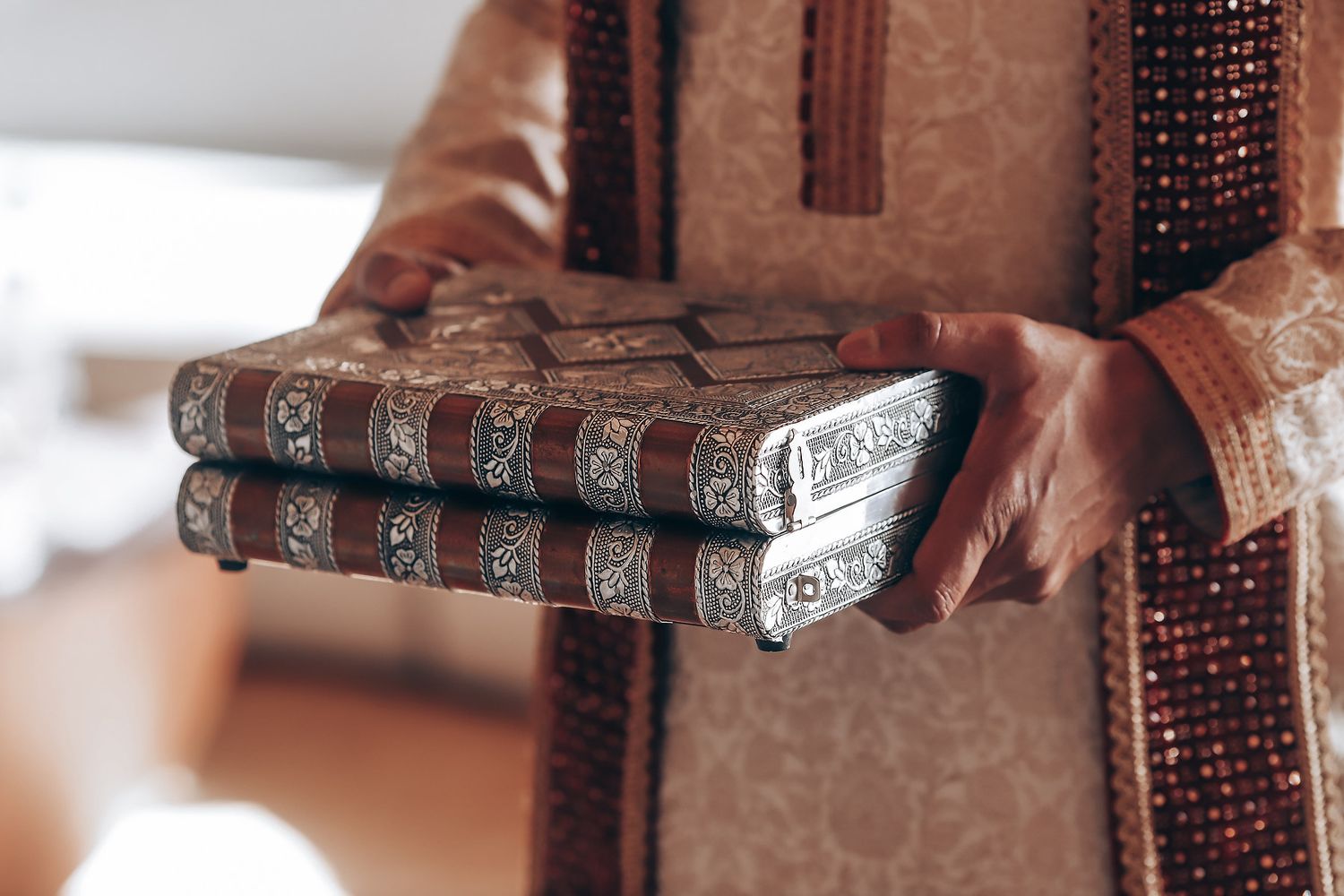 A row of vintage hardcover books with decorative spines displayed on a wooden surface in warm lighting.
