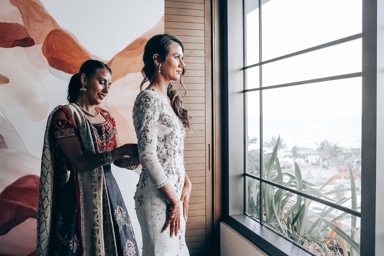 Two people stand near large windows in an industrial space while fabric billows dramatically in the air.