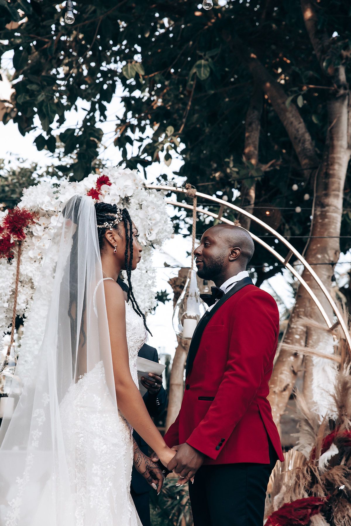 A romantic wedding couple shares tender moments under birch trees in a garden setting with flowing white veil details.