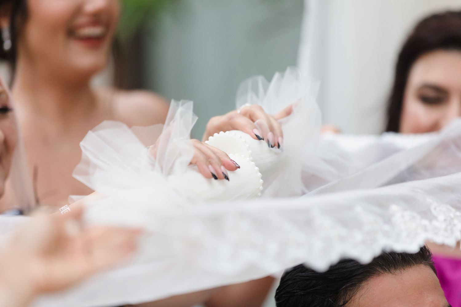 Bridesmaids holding white tulle fabric and a decorative white cupcake at a wedding celebration.