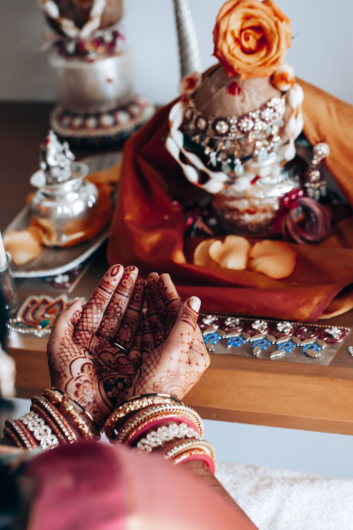 Traditional wedding jewelry and henna decorated hands with orange roses.