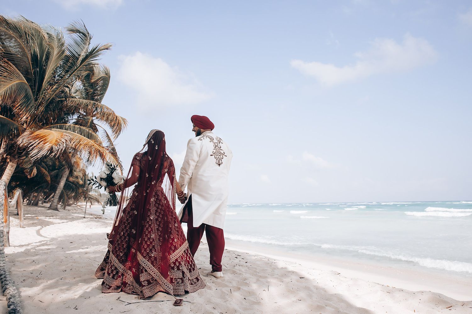 Beach wedding scene with palm trees and ocean waves in the background.