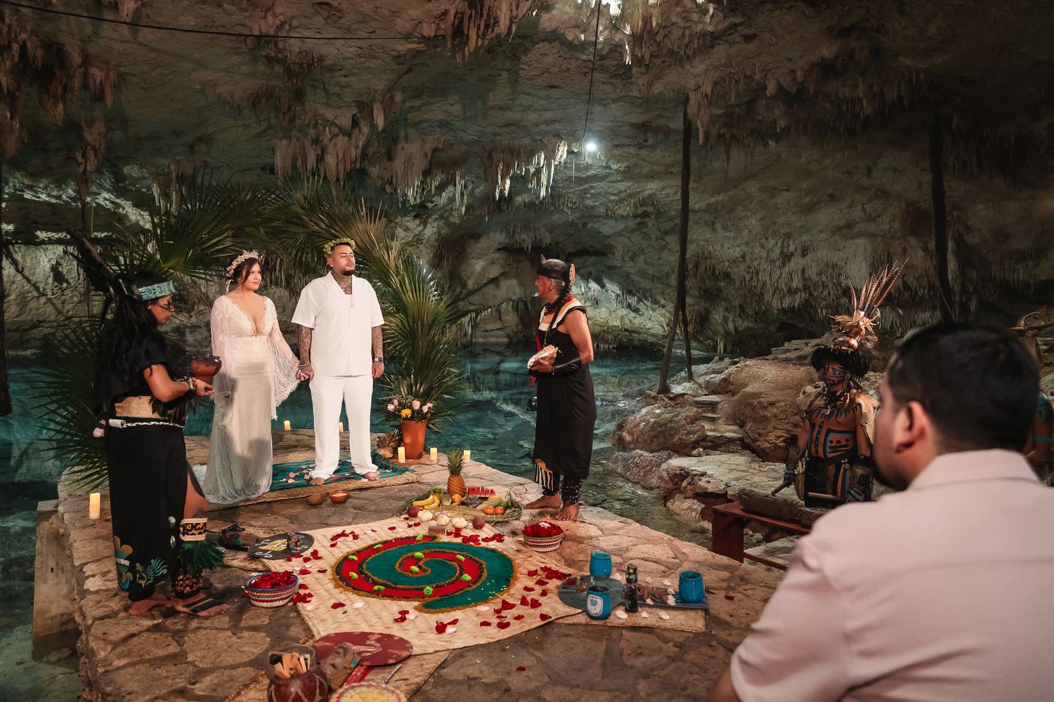 Wedding celebration in a natural cave setting with decorative lighting and floral arrangements.