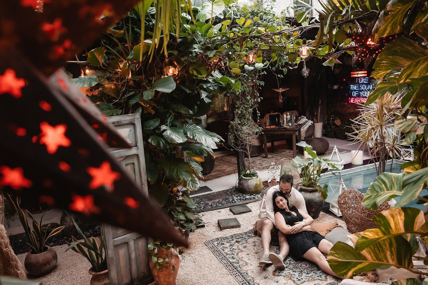 Garden scene with red star lights, tropical plants and stone pathway creating a romantic ambiance.