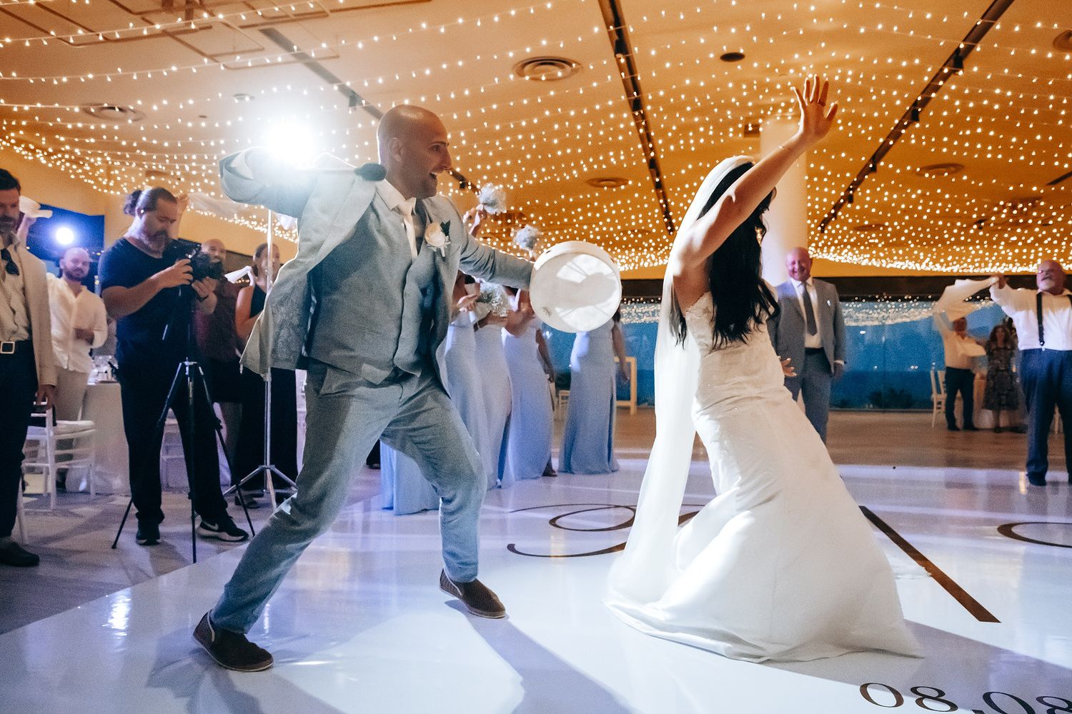 Wedding reception dance floor with twinkling lights overhead and guests dancing in celebration.