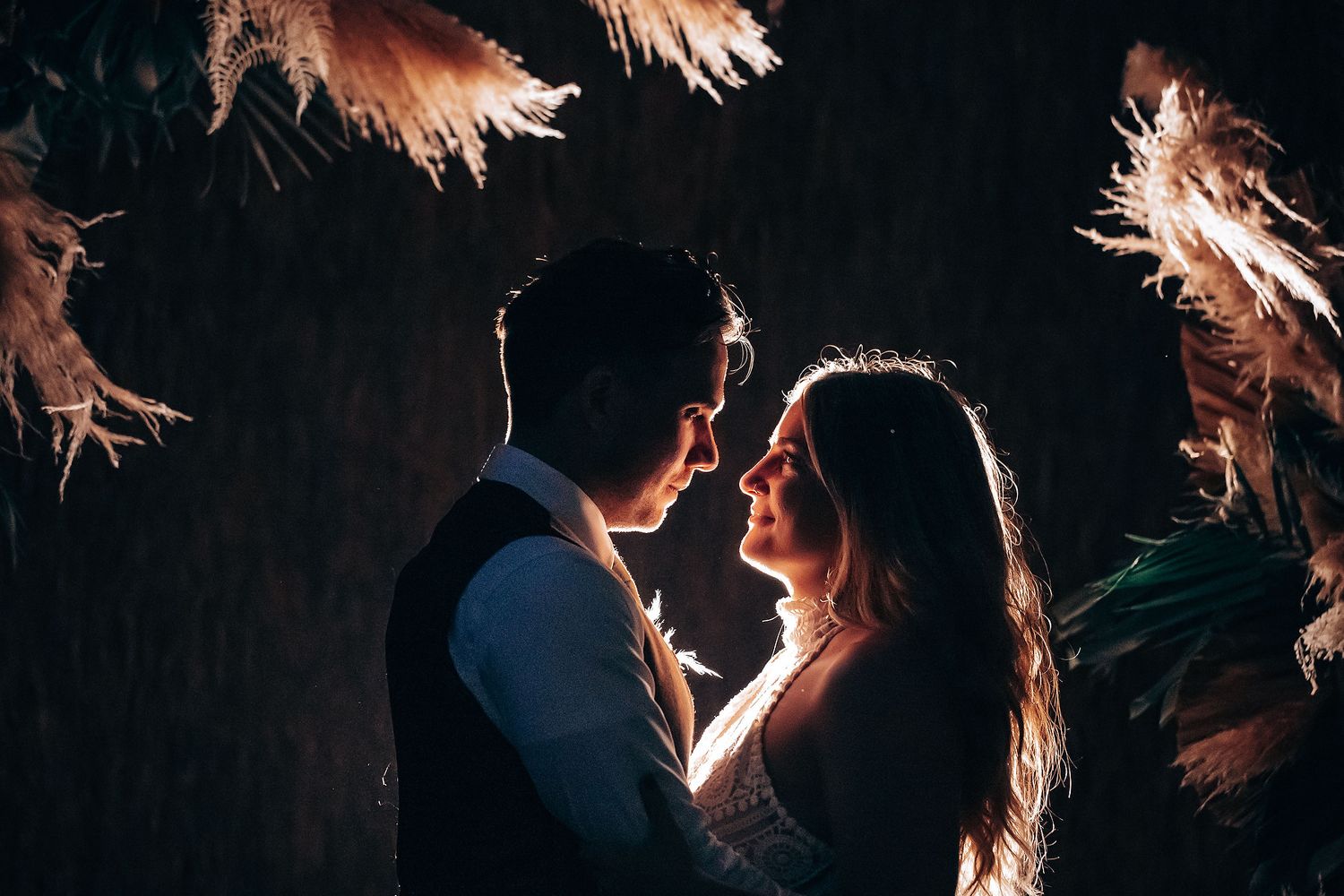 A silhouetted couple stands close together under dramatic lighting in a romantic engagement photo session.