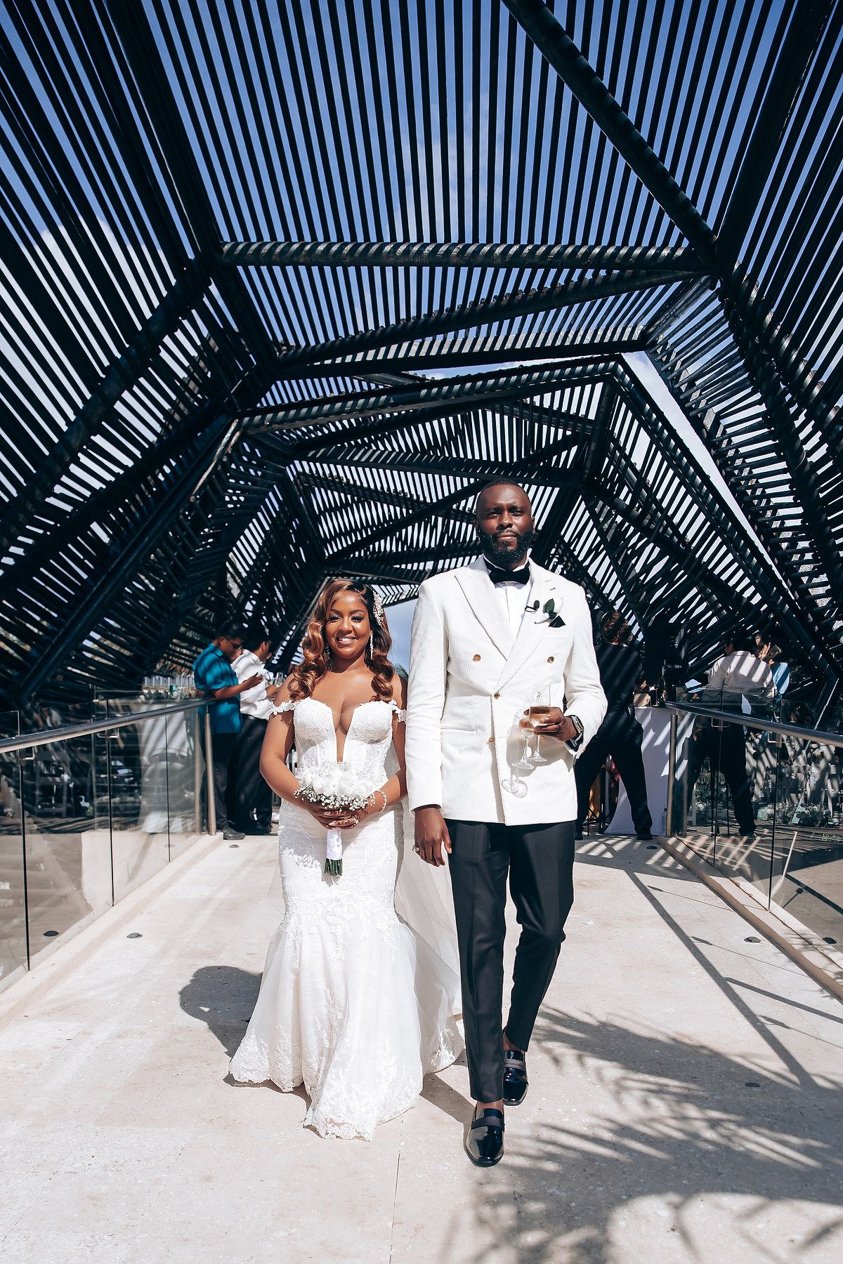 A couple walks through a modern architectural tunnel with geometric shadows and patterns.