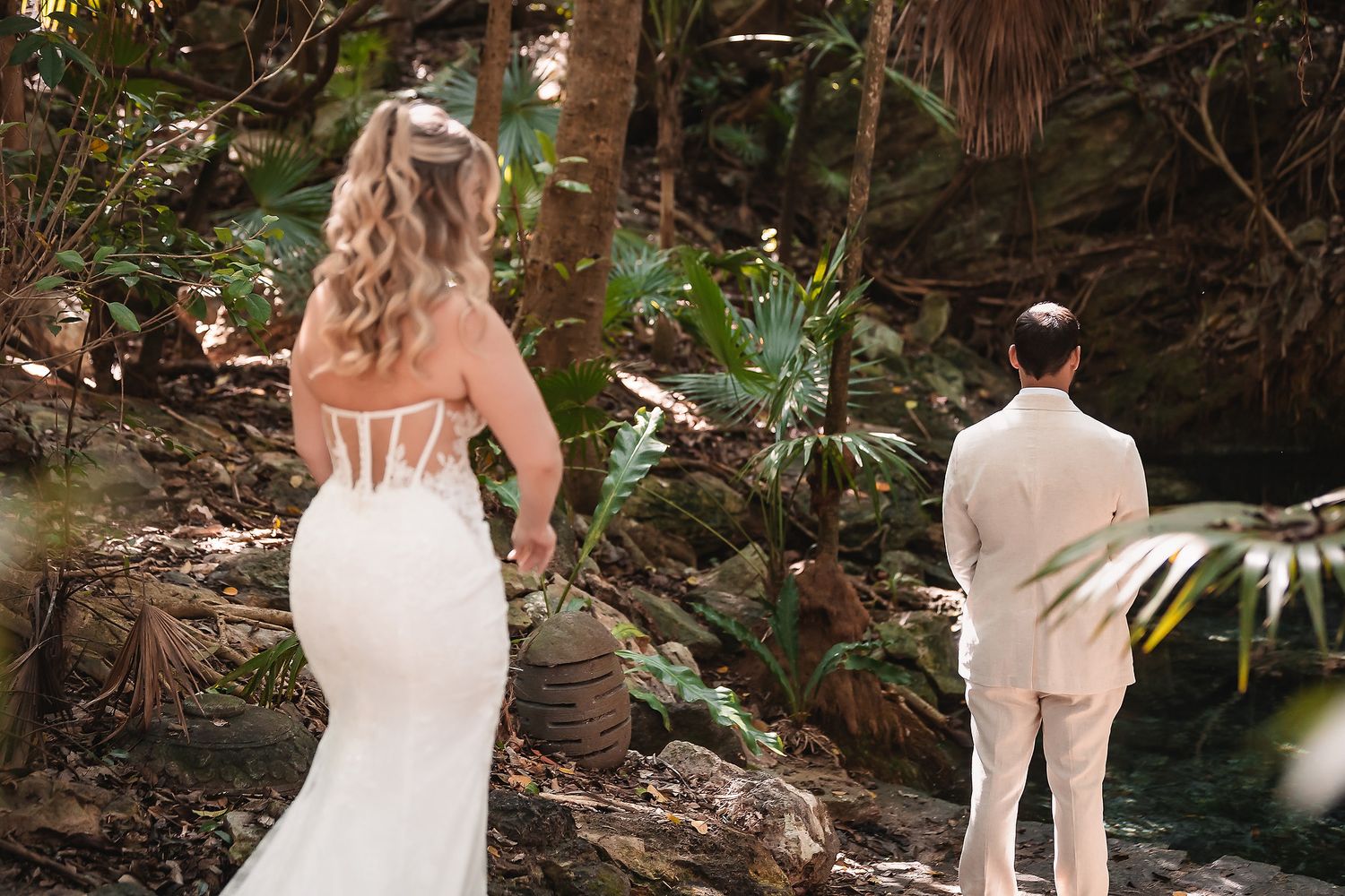 Wedding couple walking through a tropical garden path surrounded by palm trees.