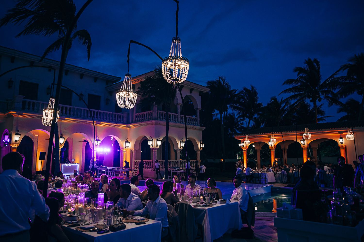 Evening wedding reception venue lit with purple lights and white lanterns.