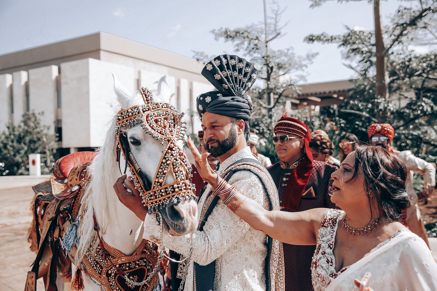 A decorated horse adorned with ornate accessories is being admired by people at an outdoor celebration.
