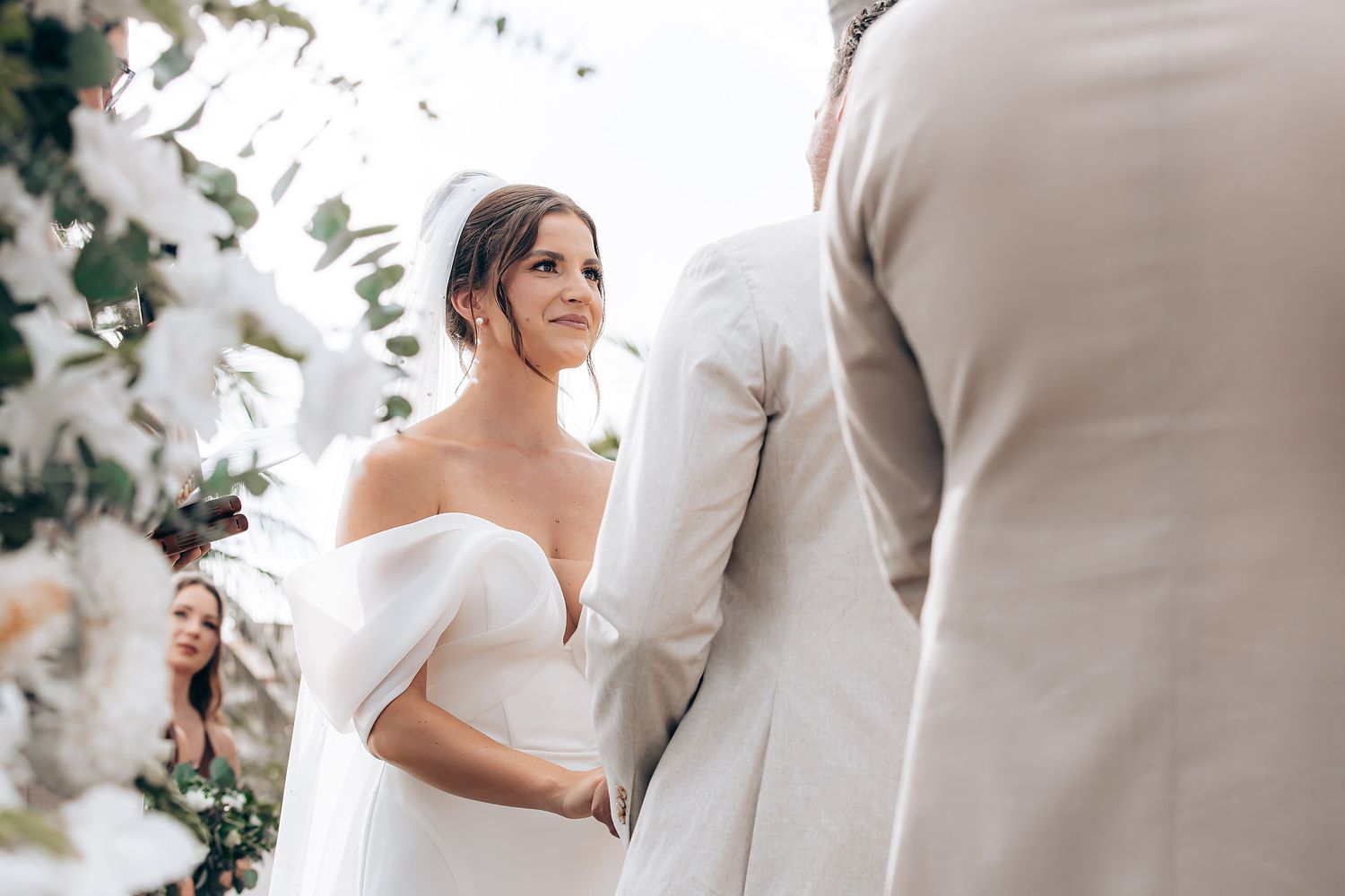 Intimate outdoor wedding ceremony with elegant floral decorations and coastal backdrop.
