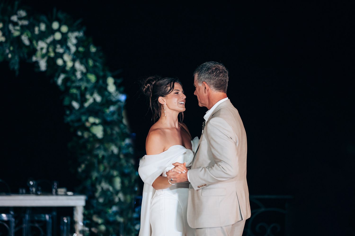 A couple shares an intimate dance moment at their wedding reception in a dimly lit setting.