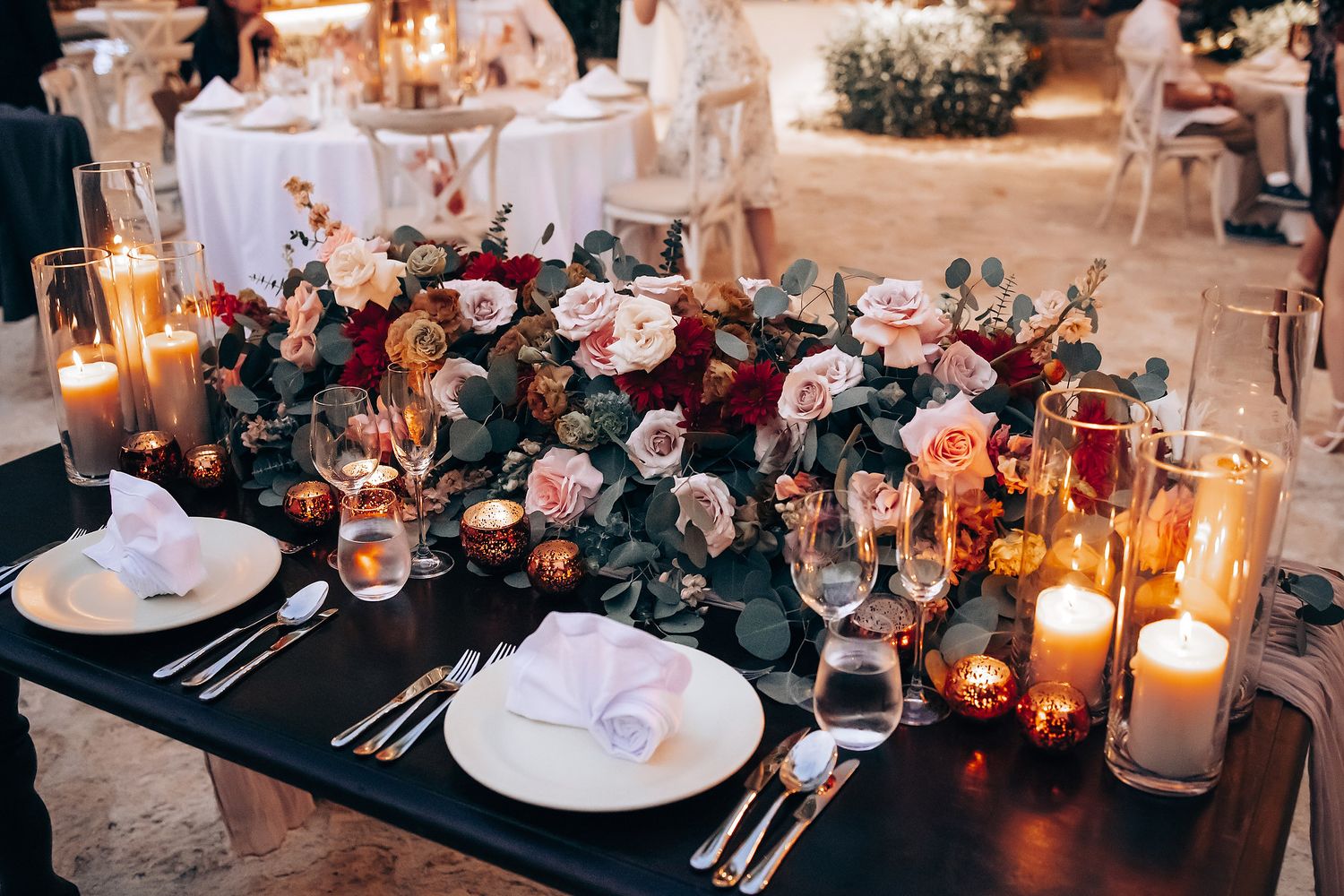 Romantic wedding reception table setting with glowing candles and elegant place settings.