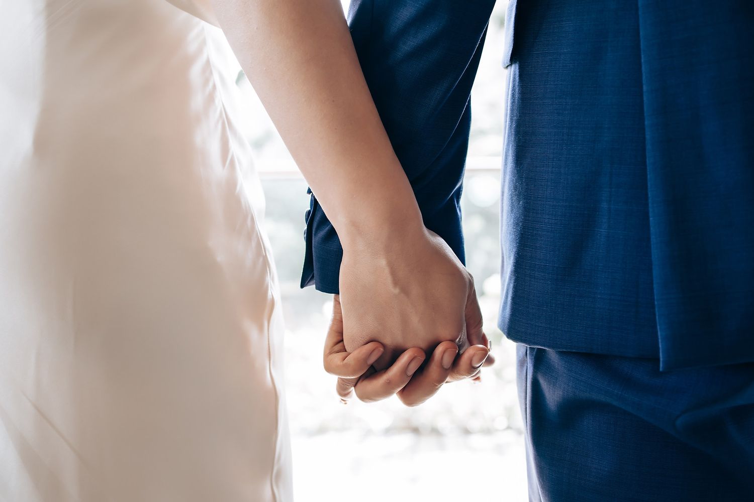 Close-up details of wedding attire showing white dress and navy suit.