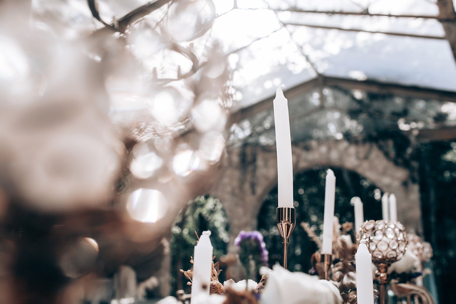 White candles and decorative elements create an ethereal ambiance at an outdoor wedding ceremony setup.