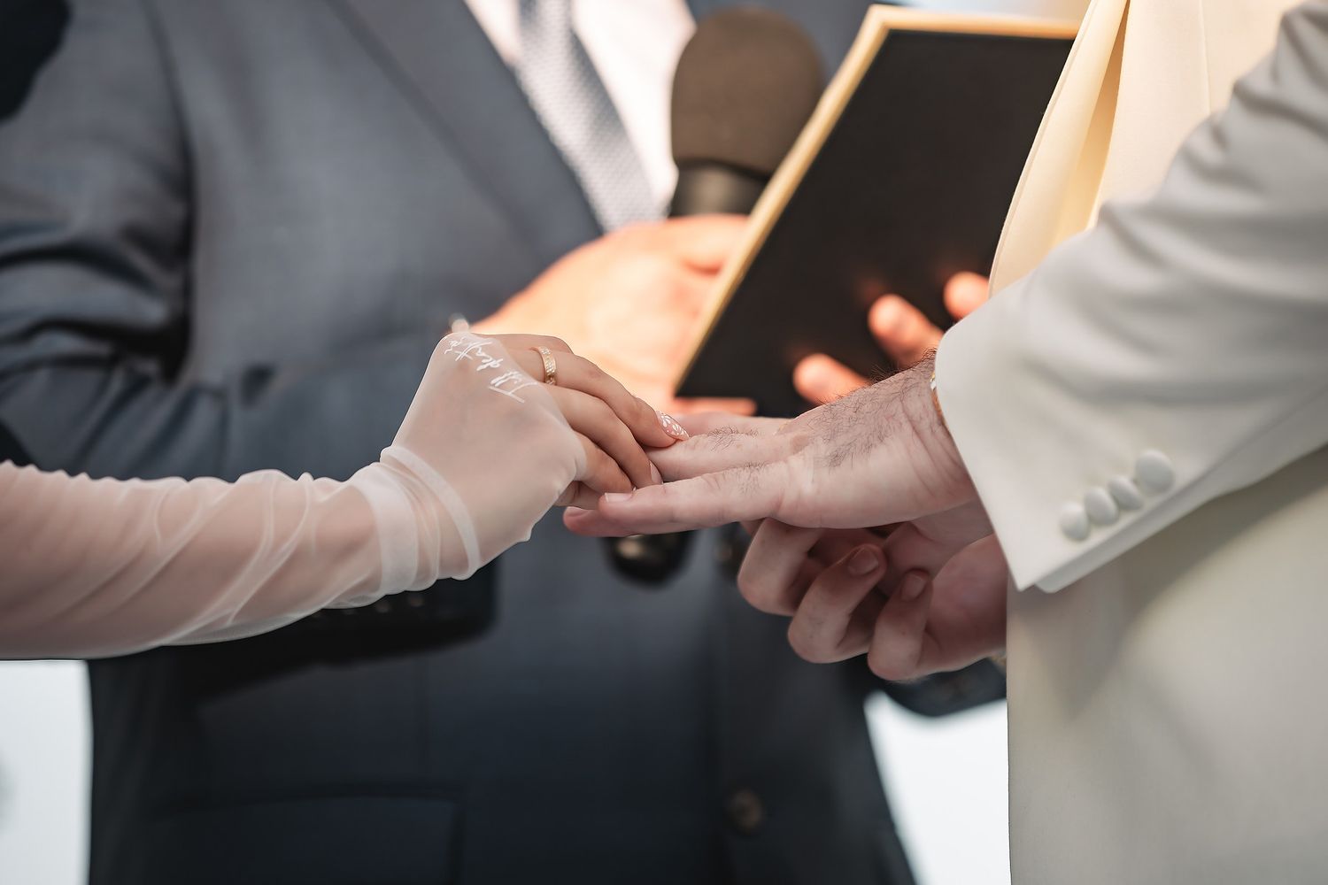 Close-up of a bride placing a wedding ring on the groom's finger during the ceremony.