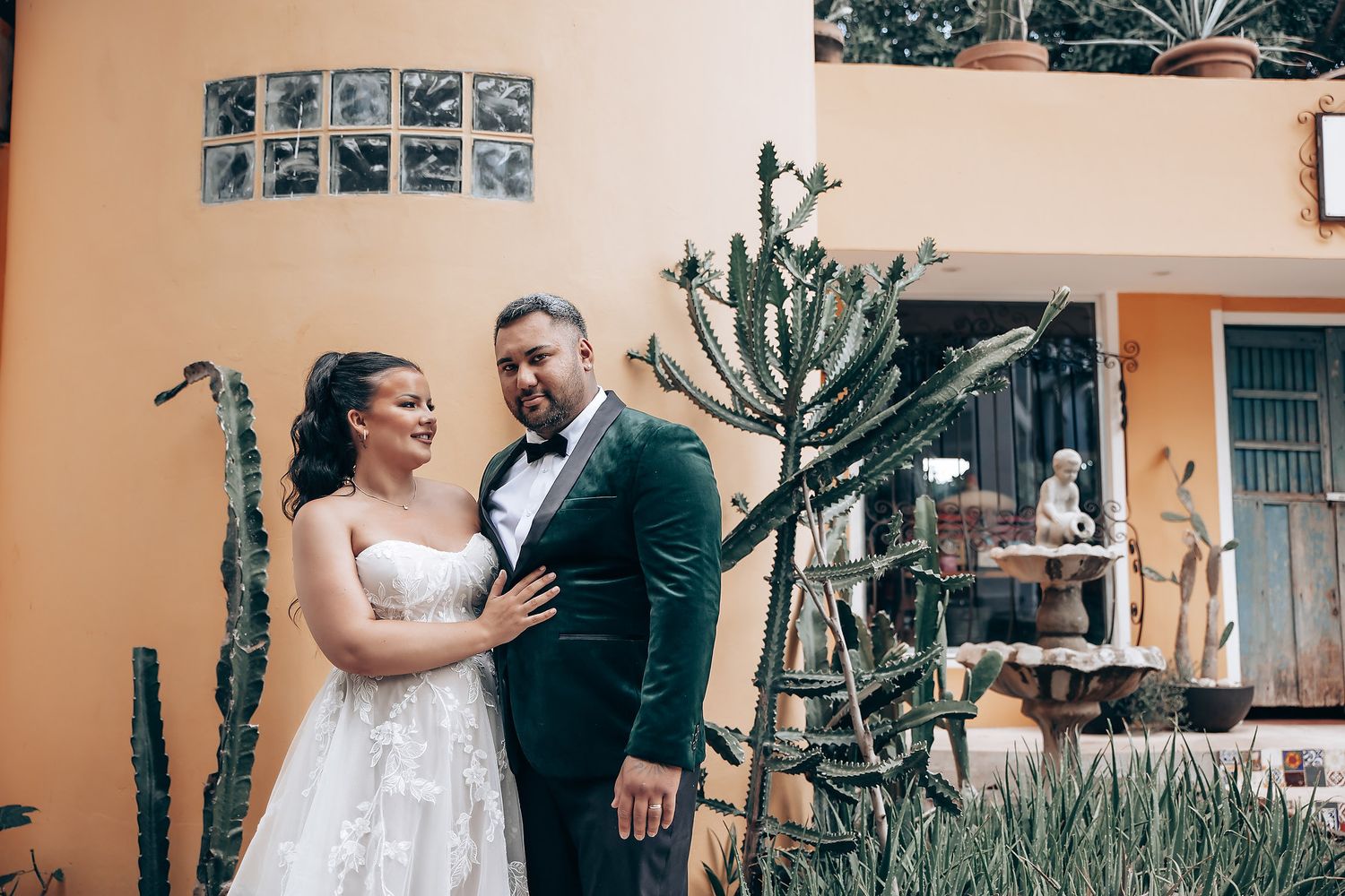 Wedding photo series against a peach-colored wall with desert plants and cacti.