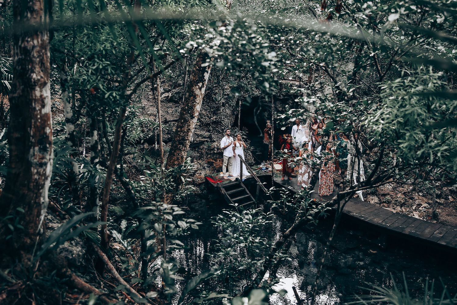 Wedding celebration in a secluded forest clearing surrounded by lush greenery.