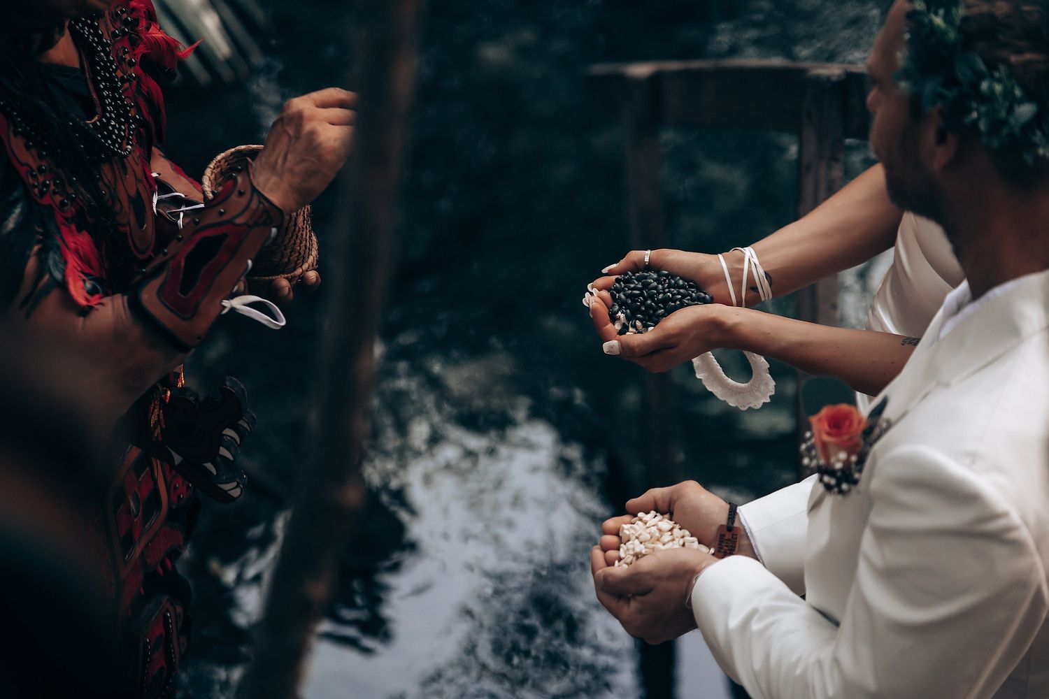 Couple in white attire celebrates their wedding ceremony in a scenic outdoor cave setting.