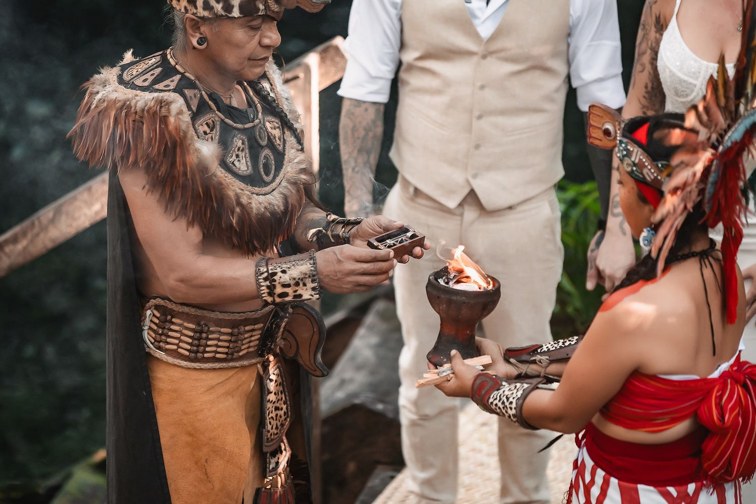 Mayan shaman performing a traditional fire ceremony ritual during an outdoor wedding celebration.