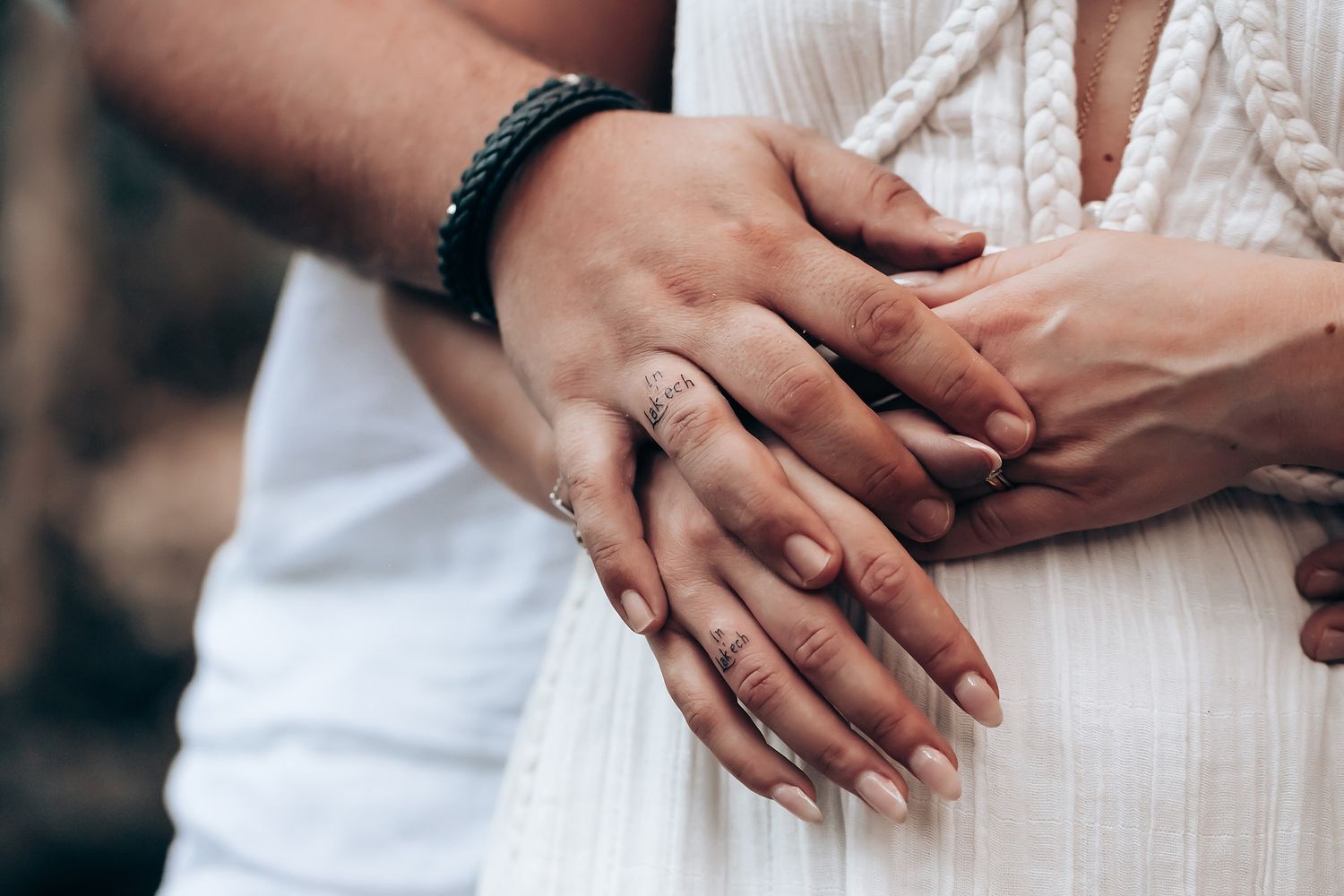 Close-up of couple's hands showing affection in white wedding attire.