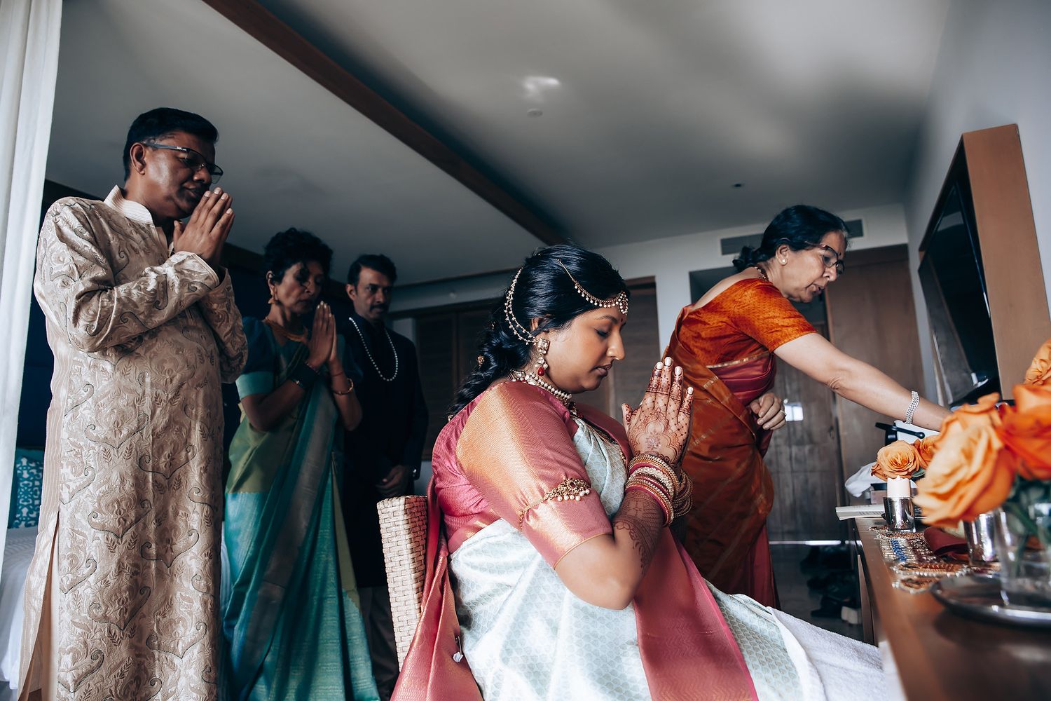 Wedding preparation scene showing multiple people getting dressed in traditional Indian attire.
