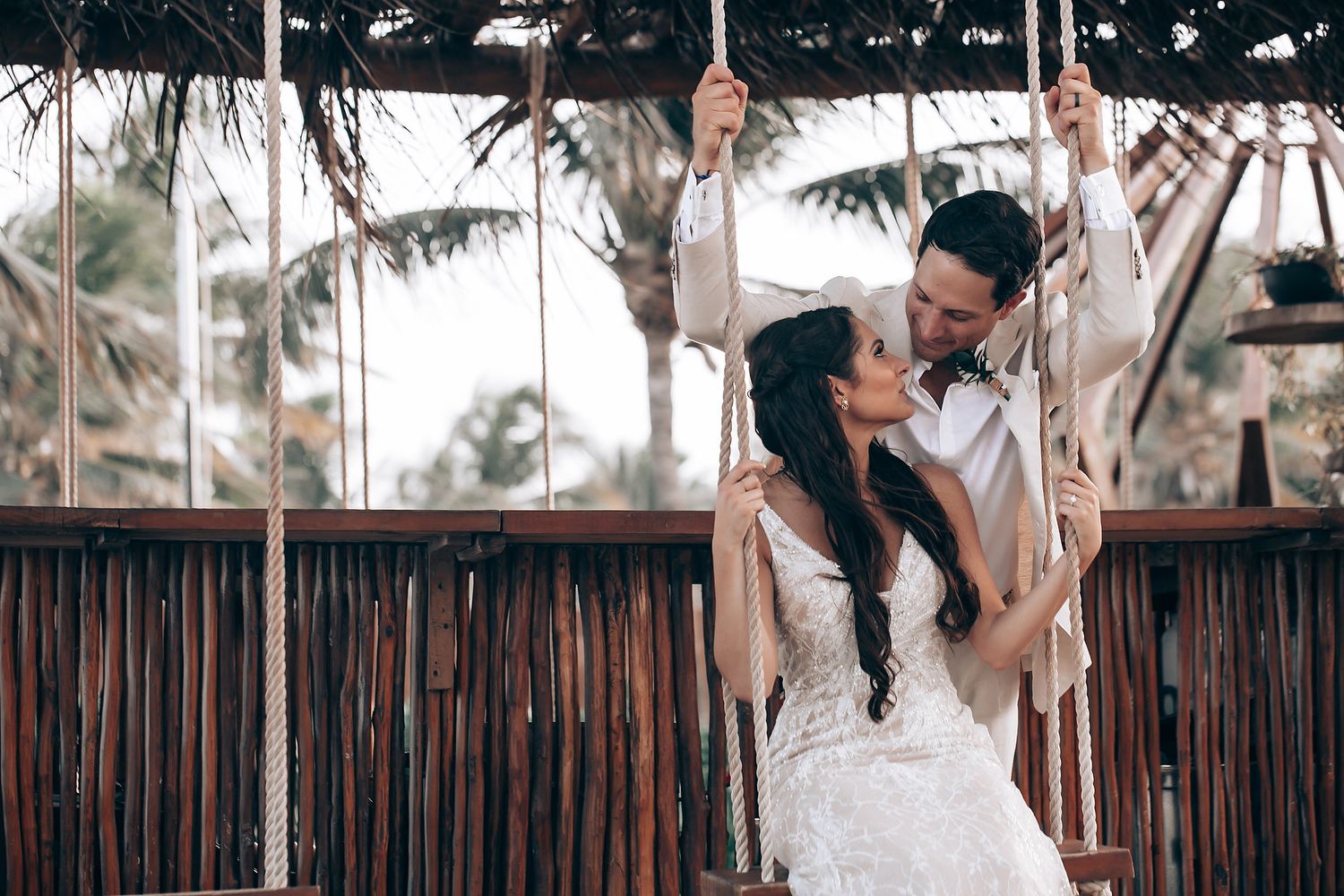 Tropical wedding scene with palm trees and romantic moments on a wooden deck.