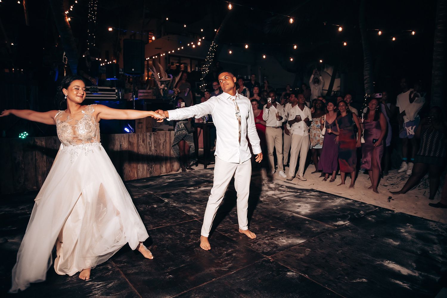Wedding reception dance party at night with string lights creating a romantic atmosphere.