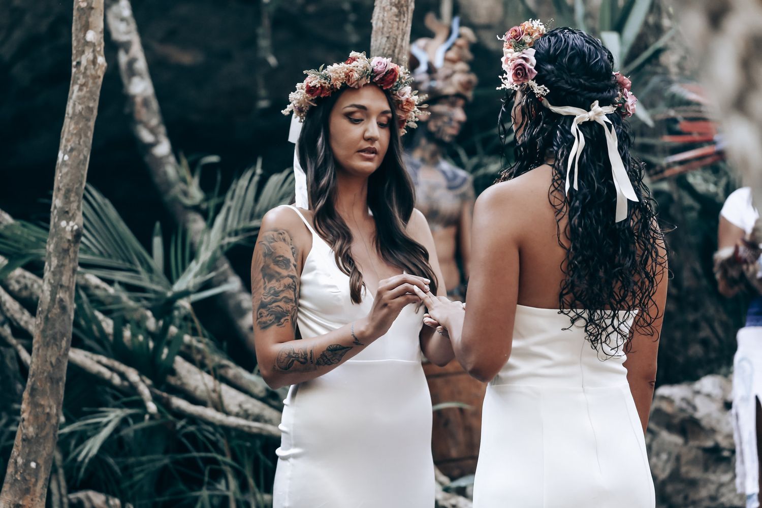 People in white and dark clothing gather in a lush outdoor setting for what appears to be a spiritual ceremony.