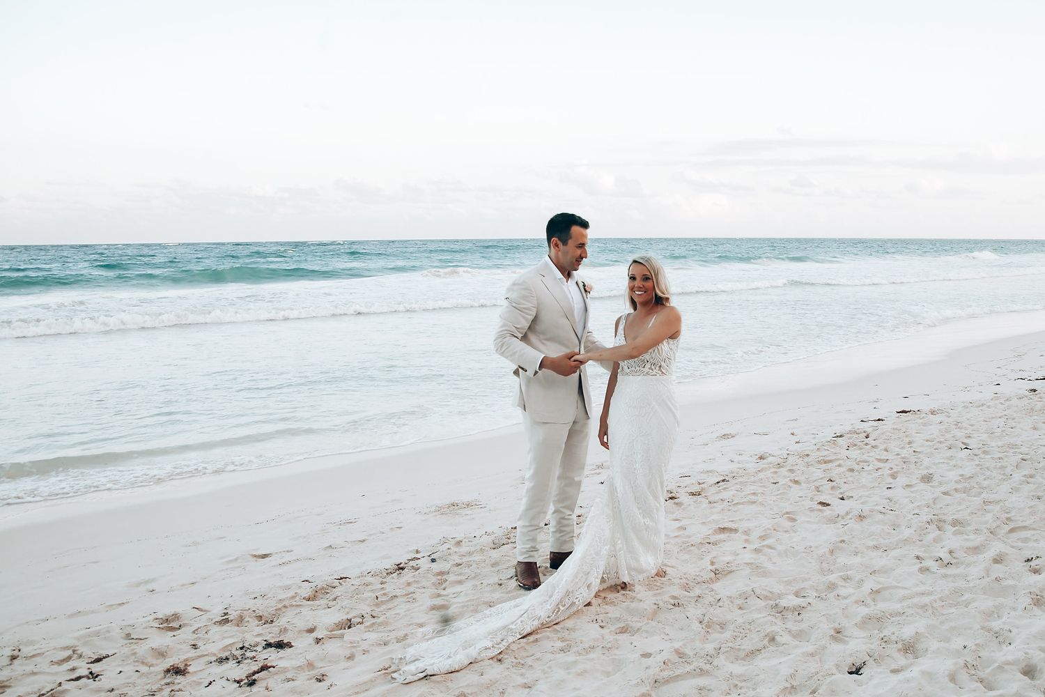 Romantic beach wedding portraits with waves and white sand in the background.
