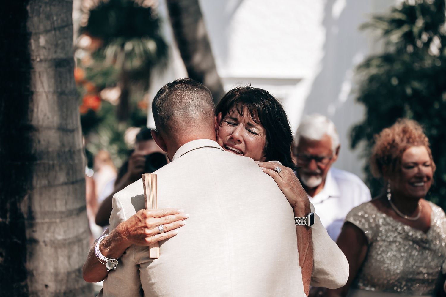 A couple in formal attire embrace during their outdoor wedding ceremony.