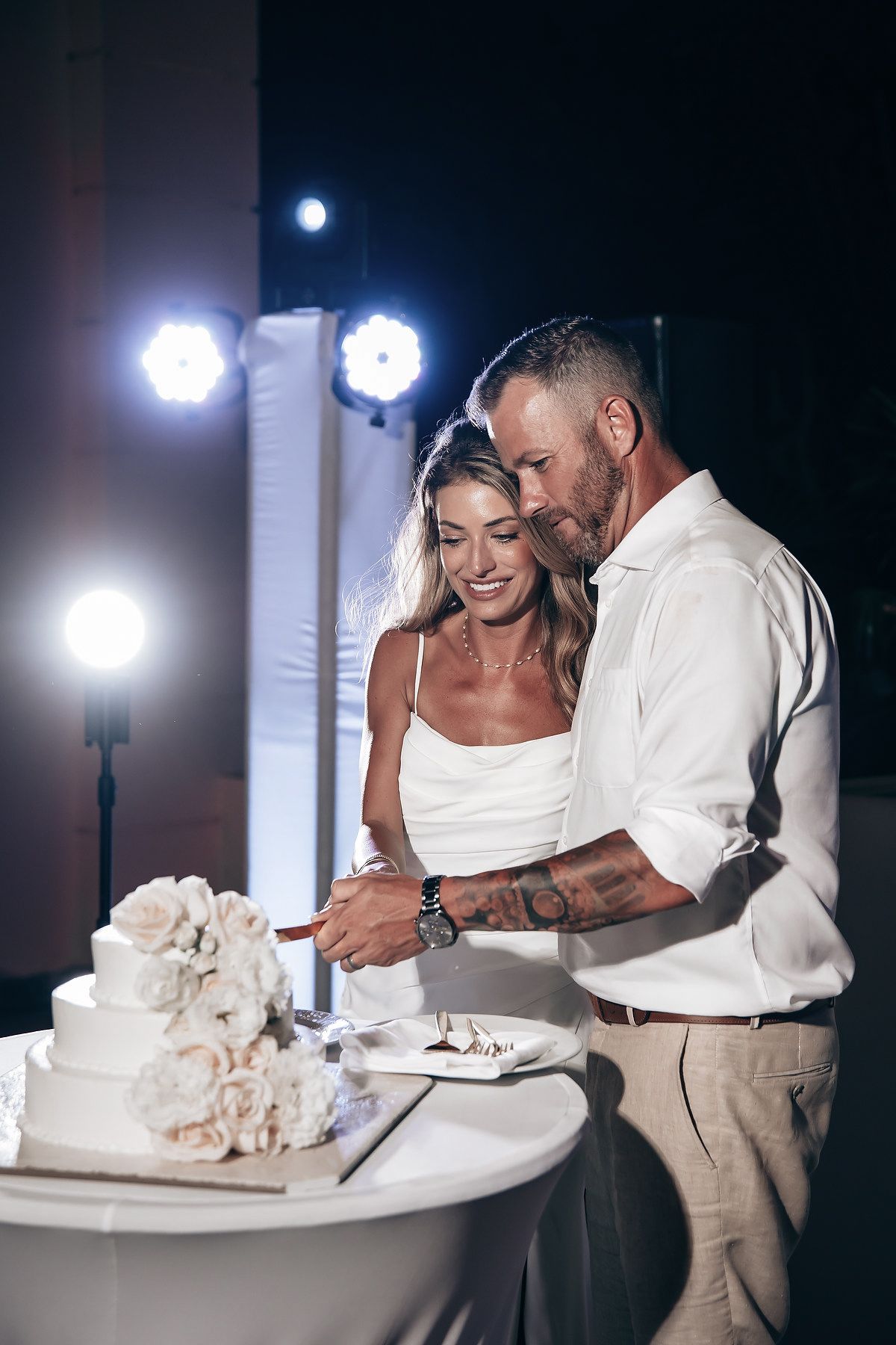 A couple cuts a wedding cake together at a reception.