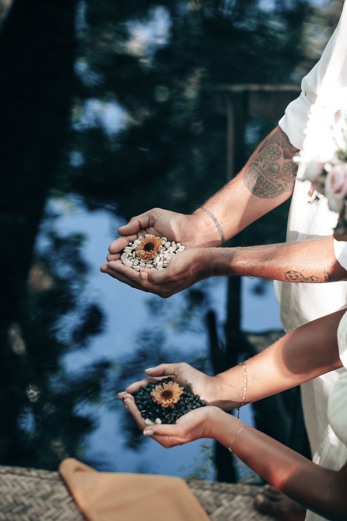Hands holding a handful of flowers and leaves in an outdoor setting.