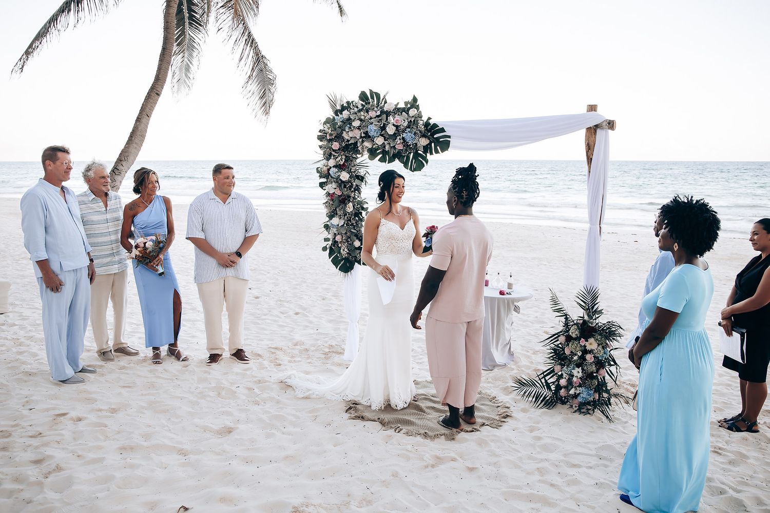 A wedding ceremony taking place on a beach with the couple and guests.