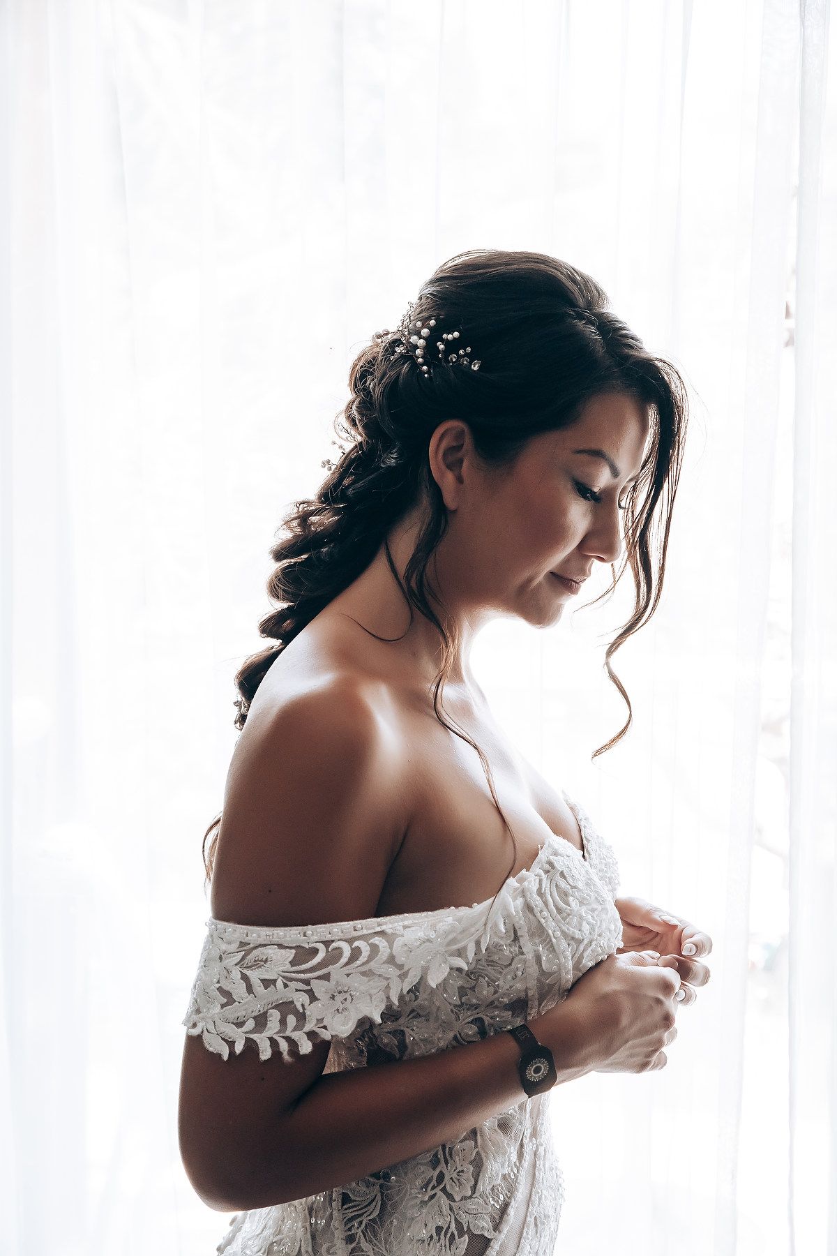 A series of black and white portraits showing an off-shoulder lace wedding dress in natural window light.