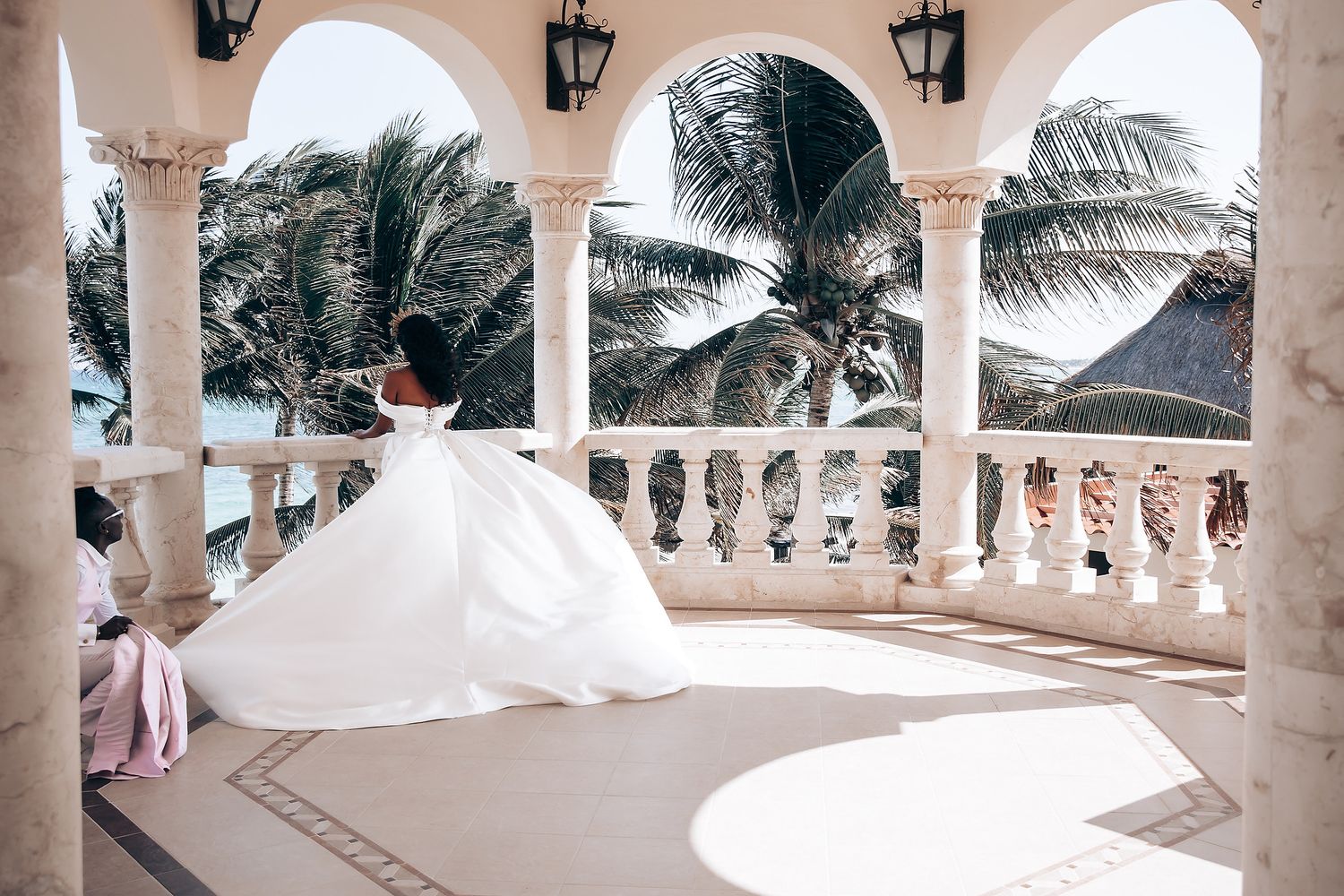 White wedding ceremony venue with elegant columns and palm trees creating a romantic tropical atmosphere.