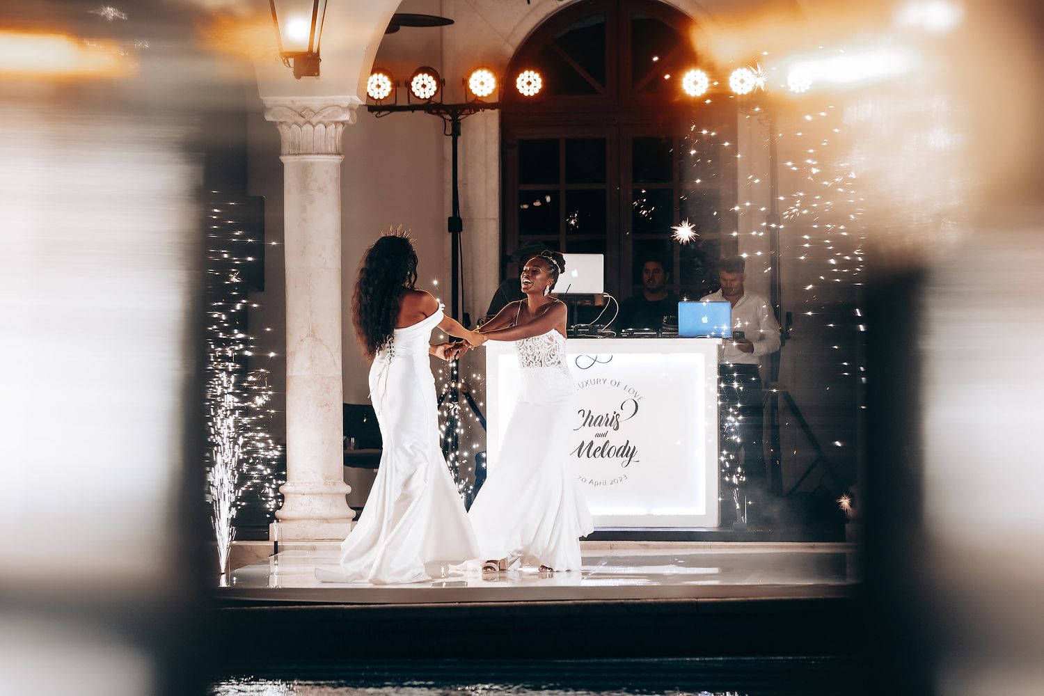 Evening wedding reception with glowing lights and reflections across an illuminated venue.