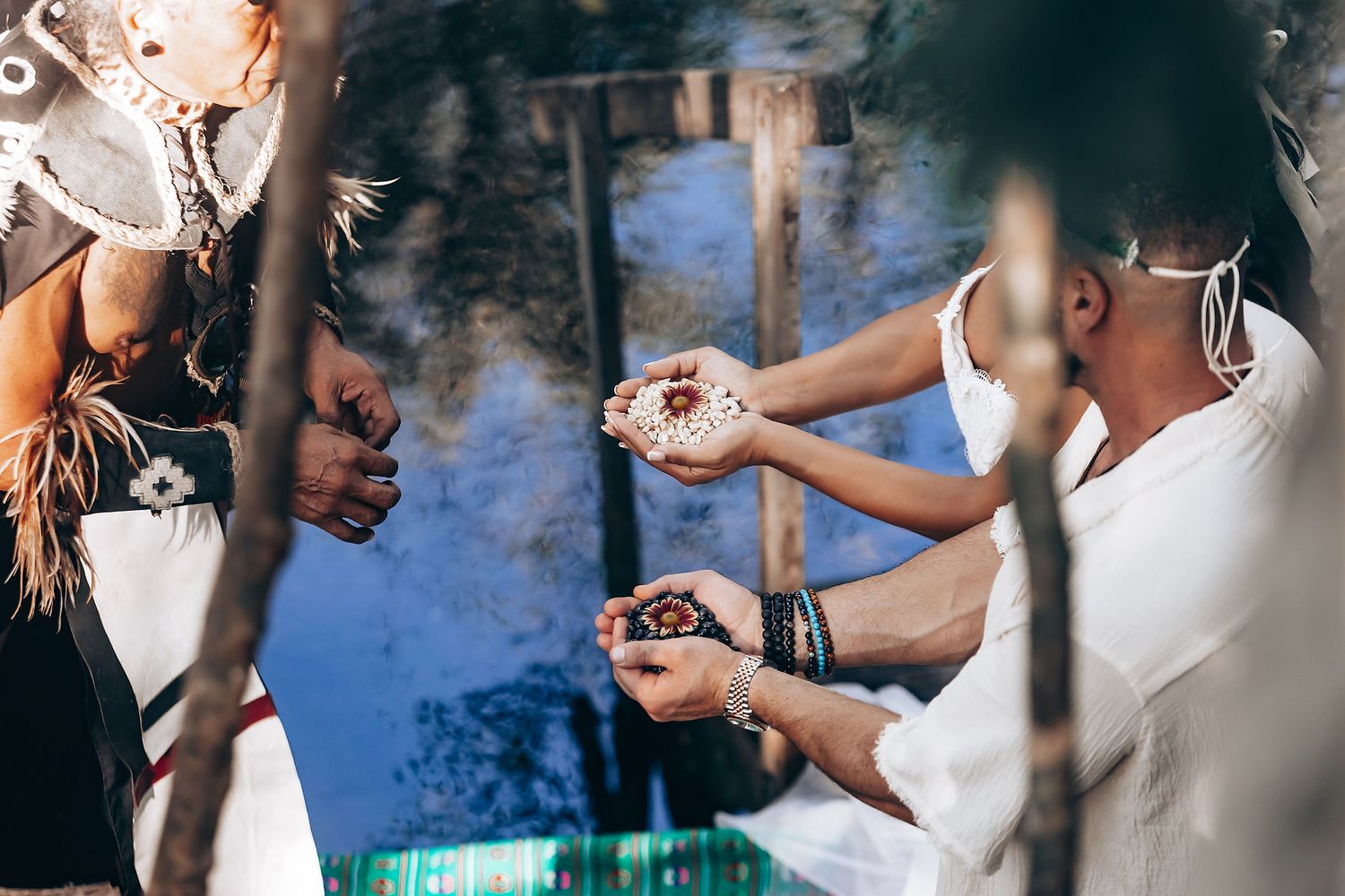 Wedding party enjoys festivities near a reflective water feature in a natural setting.