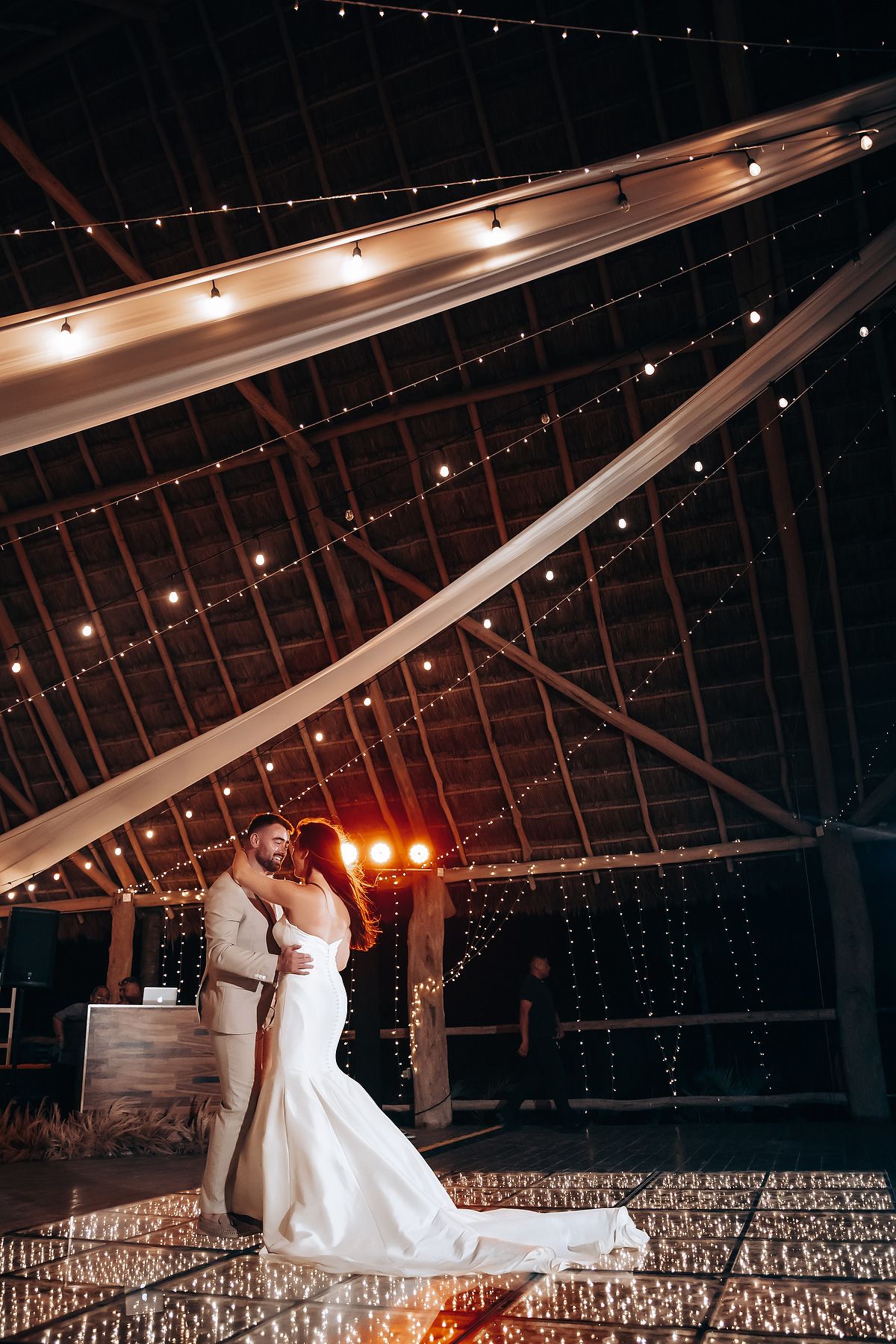 Romantic dance scene in a dimly lit rustic barn with twinkling lights and dramatic ceiling beams.
