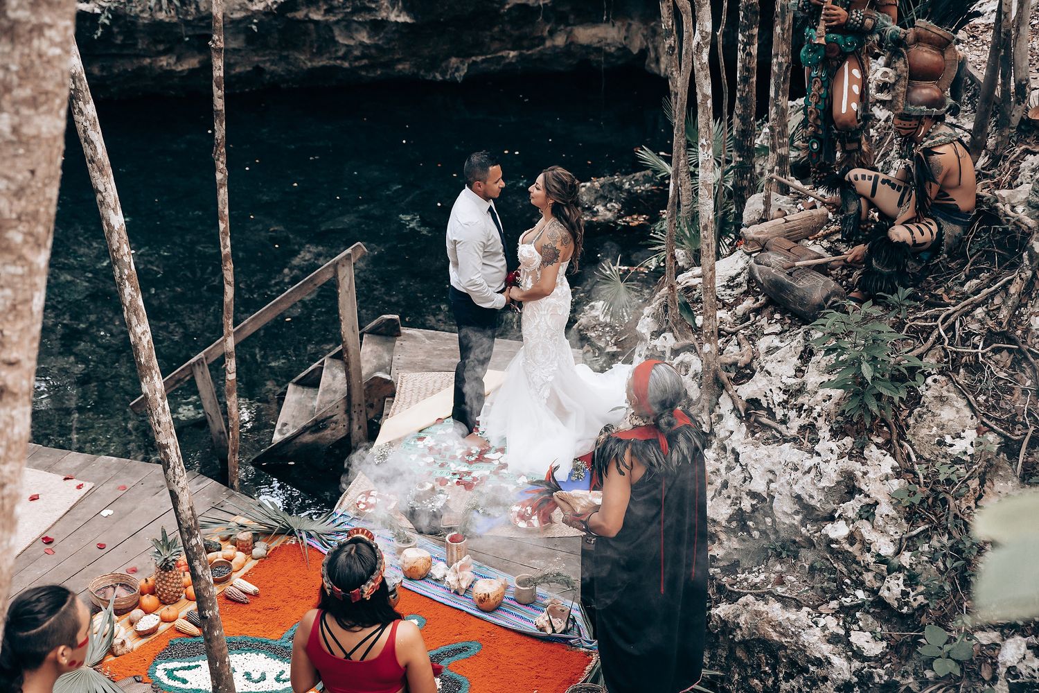 Guests enjoying a festive outdoor wedding reception with string lights and rustic decor in a forest setting.