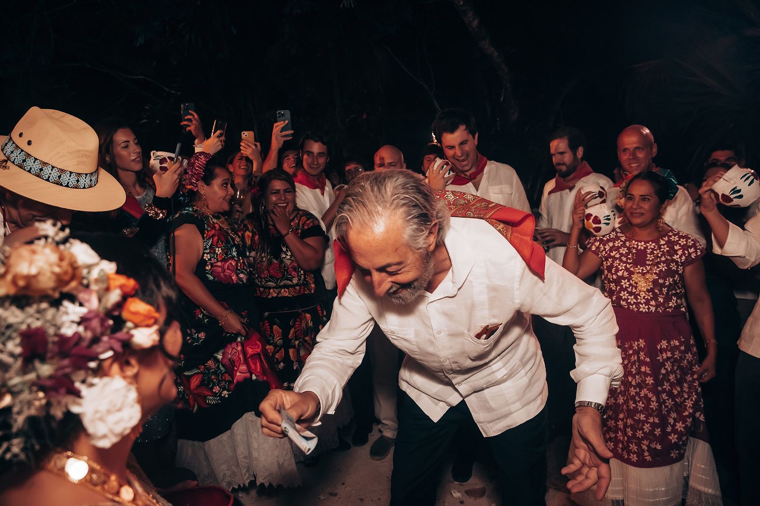 Guests dancing and celebrating at a lively wedding reception under string lights.