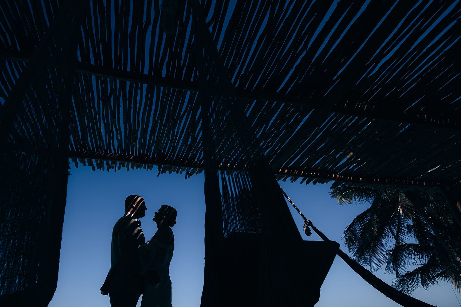 Dramatic silhouettes against deep blue sky create artistic wedding photography.