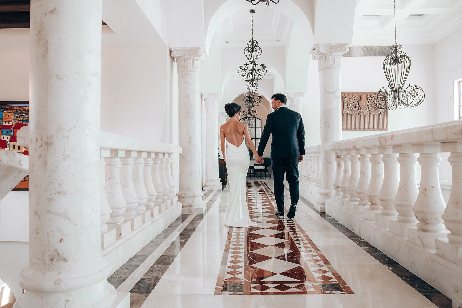 A series of elegant wedding photos showing a couple walking through a white columned hallway with checkered floors.