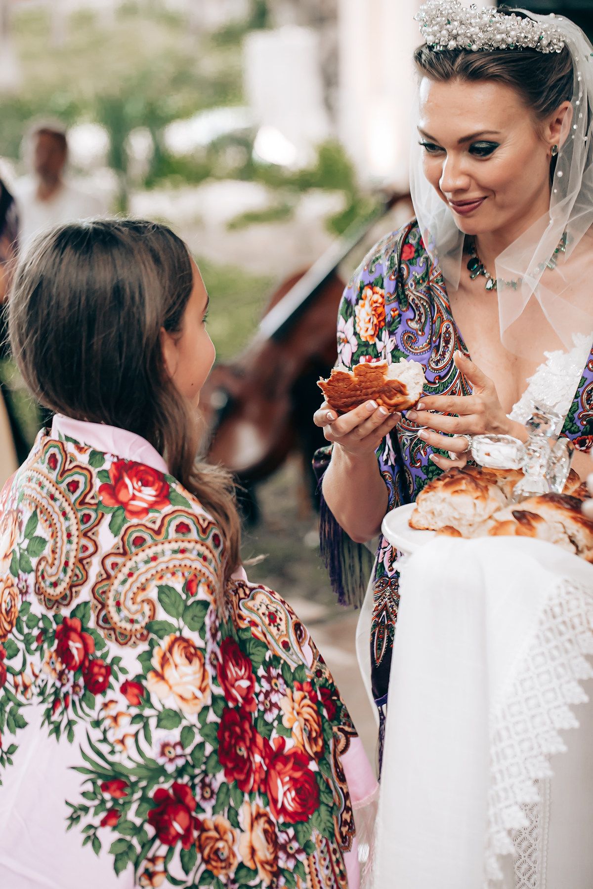 A bride in a white lace dress shares a joyful moment with guests at an outdoor wedding reception.