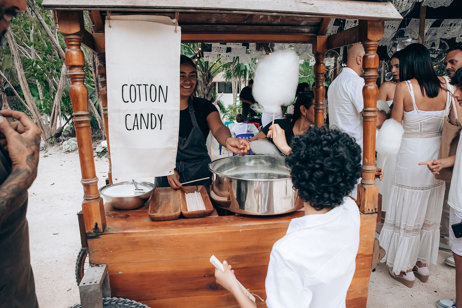 Wedding reception setup with rustic wooden bar and white decor elements.