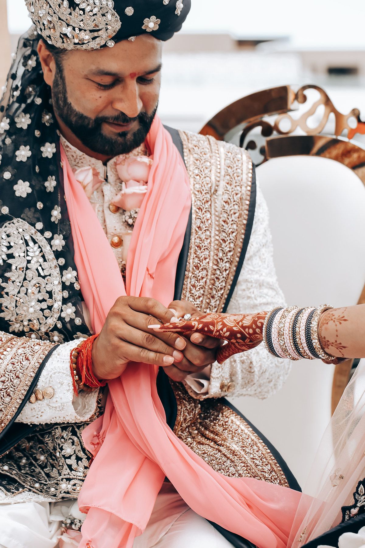 Close-up of traditional Indian wedding jewelry and attire in pink and gold tones.
